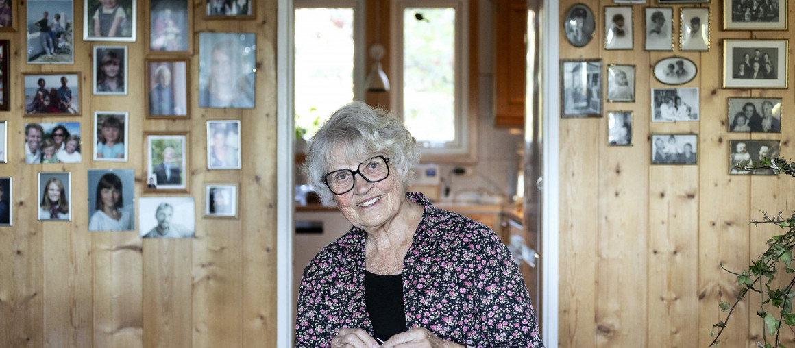 Kvinne ved bord og familiebilder bak